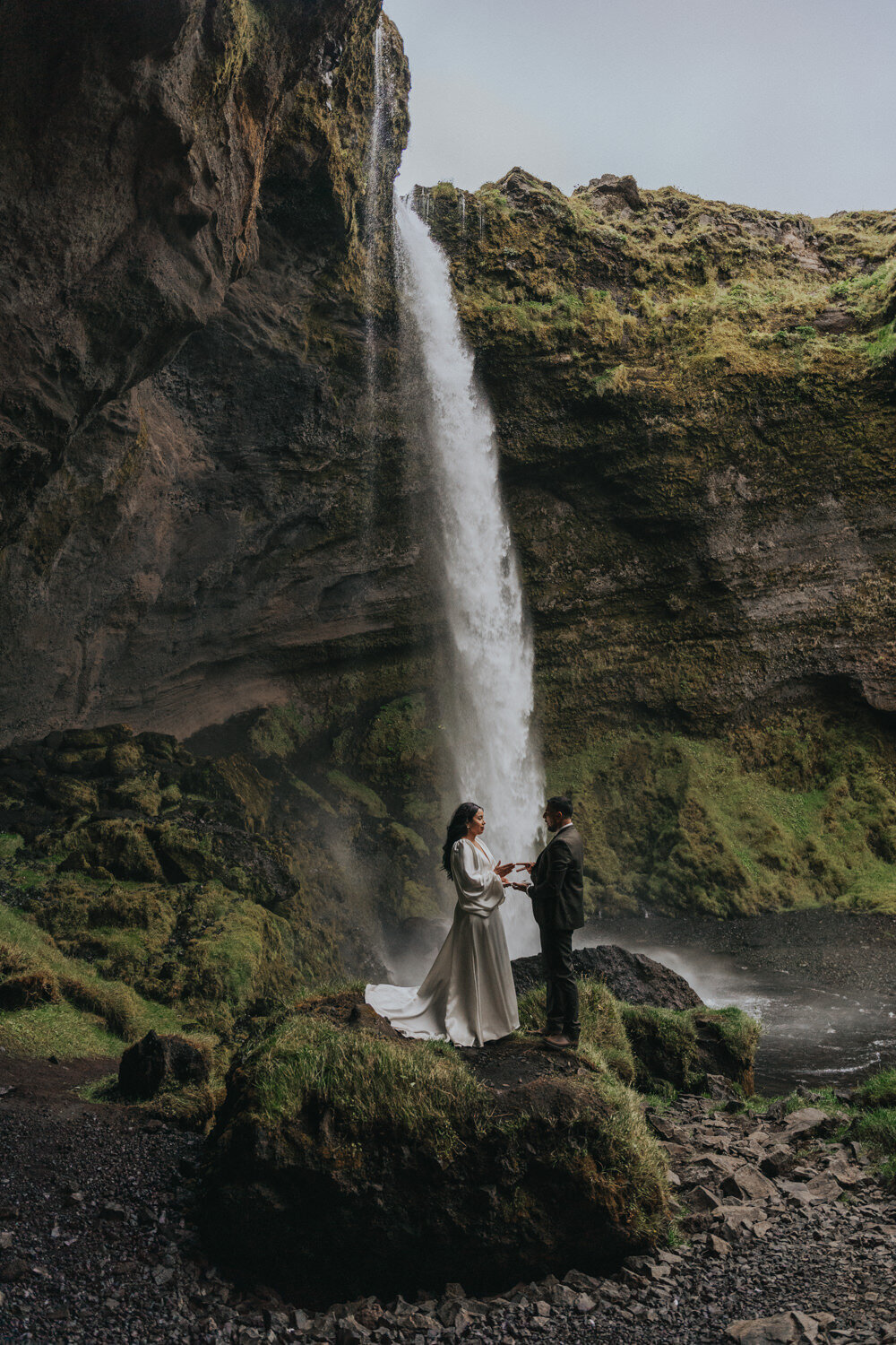 With hands intertwined, the couple exchanges vows near a quiet, secluded waterfall