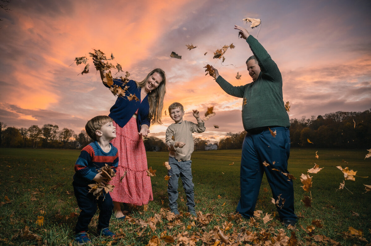 Family of 4 playing with leaves at sunset in a lincoln, MA hayfield
