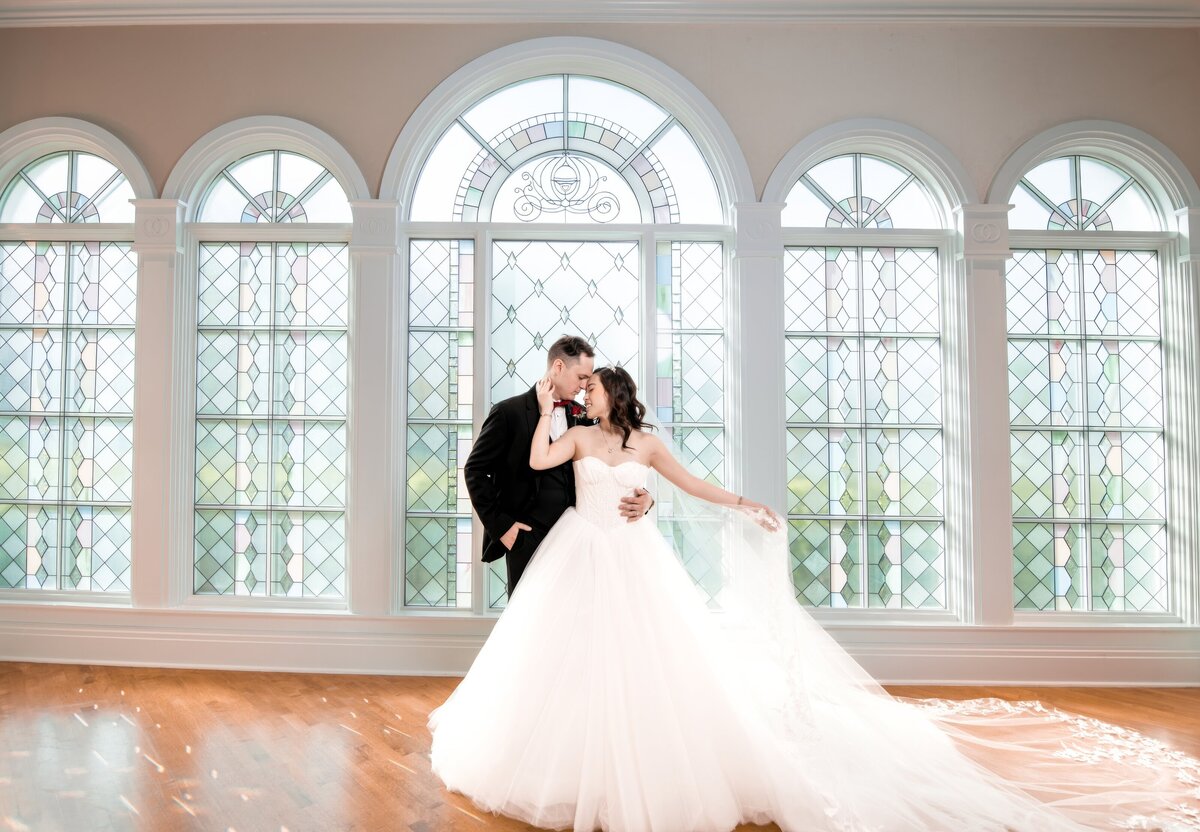 bride and groom pose romantically in front of Disney World venue windows