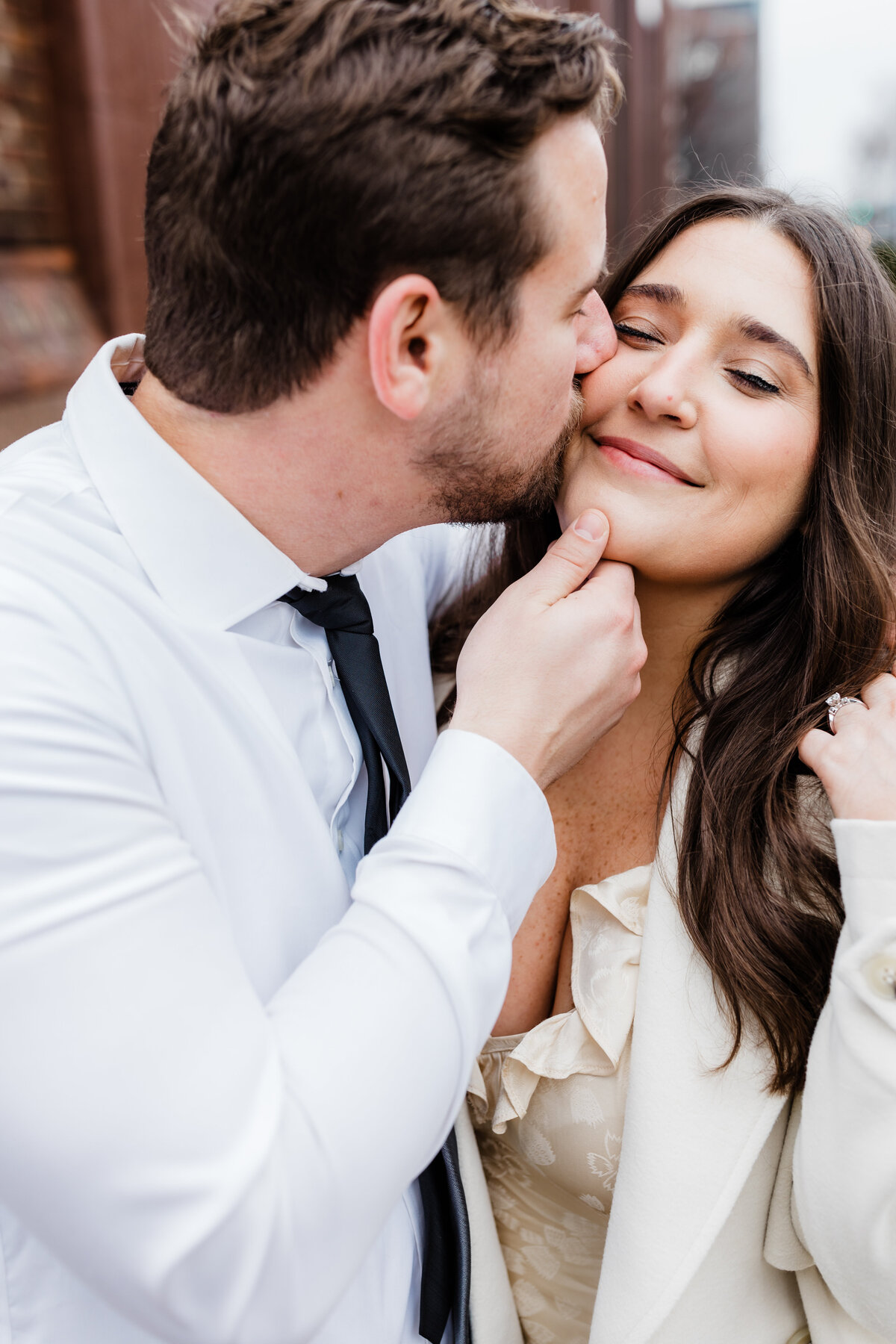 Groom-to-be kissing his fiancée’s cheek during a playful engagement session in South Bend, Indiana.