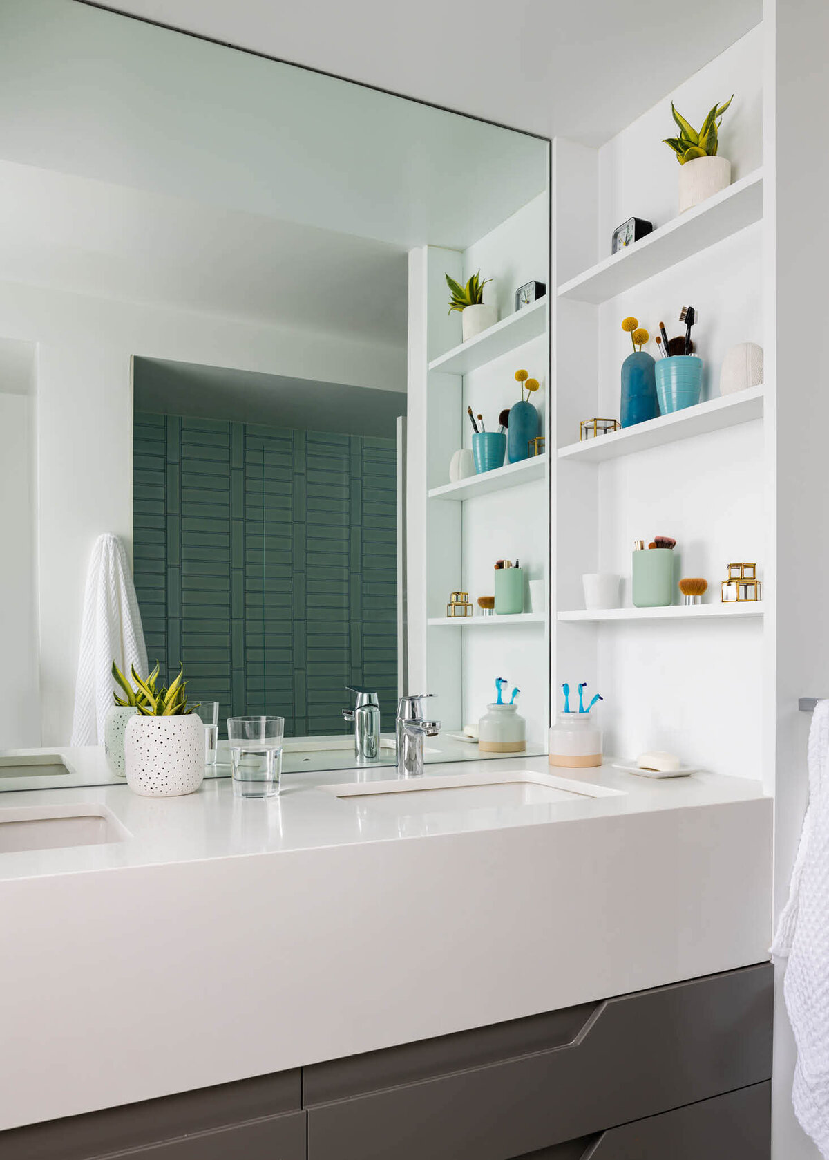 Cambridge interior designer creates a kids' bathroom with a custom vanity featuring dark grey drawers, a white stone apron and counter, and built-in white storage shelves.