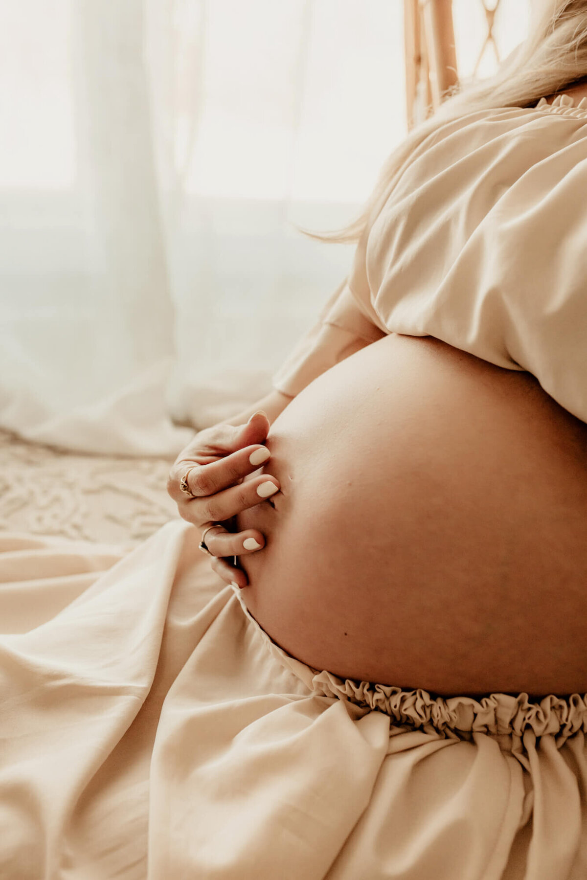 Baby bump photo of mother touching her belly.