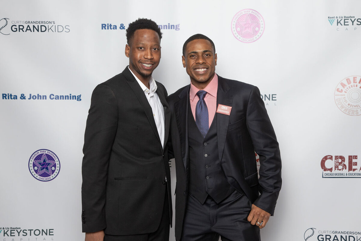 Two men in suits at step-and-repeat backdrop