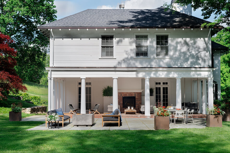 Covered porch and new patio at a historic Concord home, with furniture selected by a Boston interior decorator, blending modern style with classic charm. 