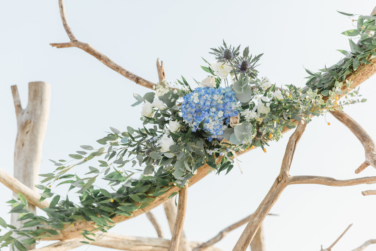 A close up of a chuppah with blue and white flowers