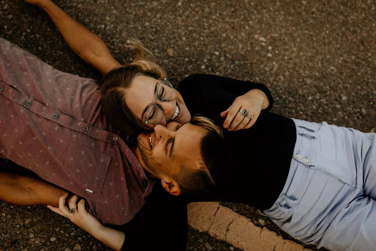 engaged couple sitting on a bike trail in Albuquerque laughing