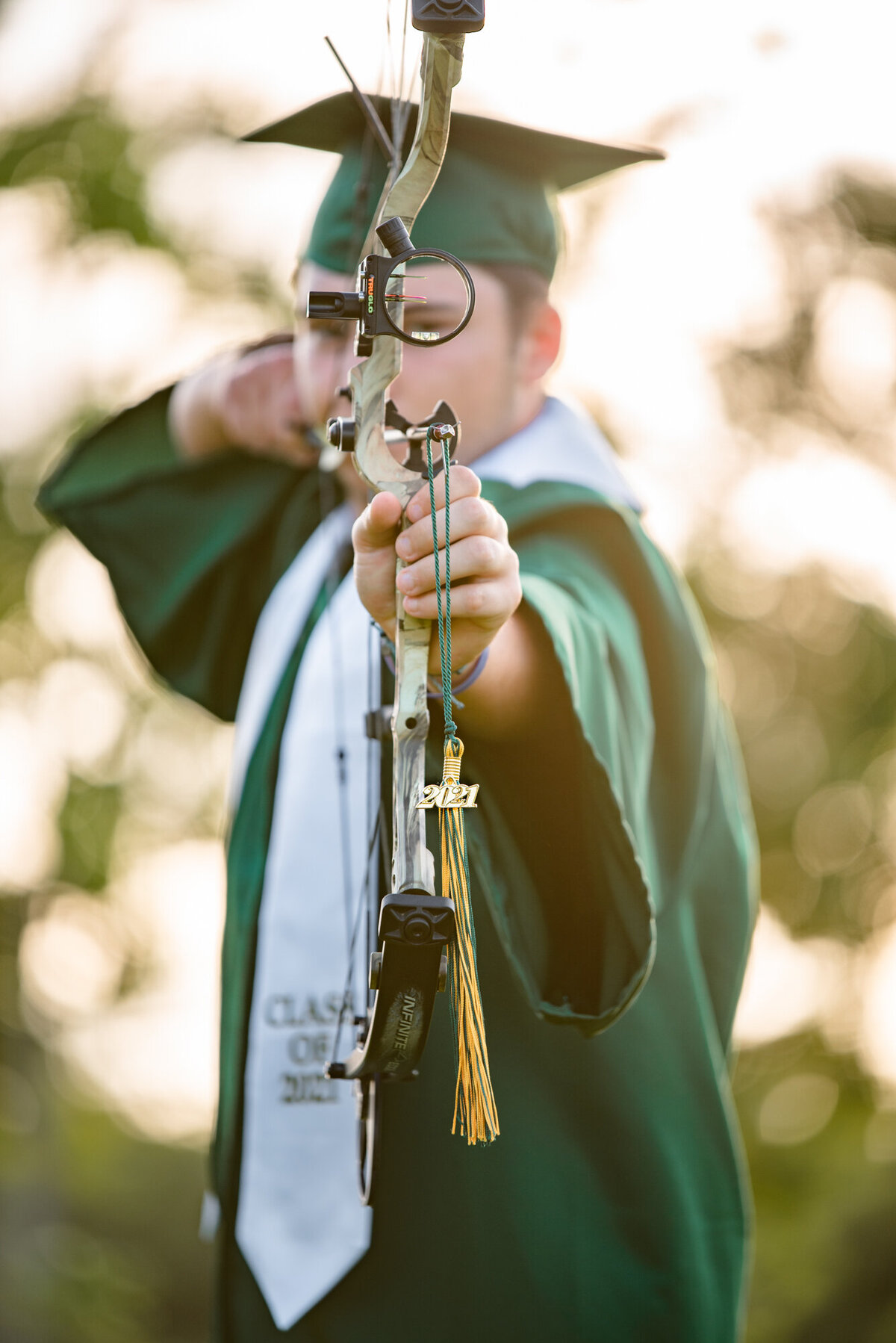 A Santa Fe High School senior wears his cap and gown while balancing his tassel on his bow and arrow.