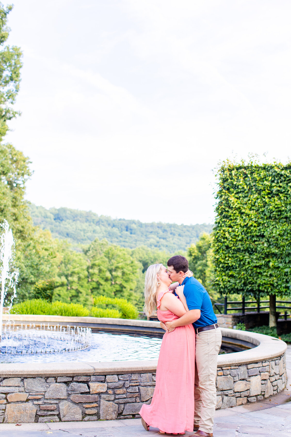 couple kissing in front of fountain with mountain views