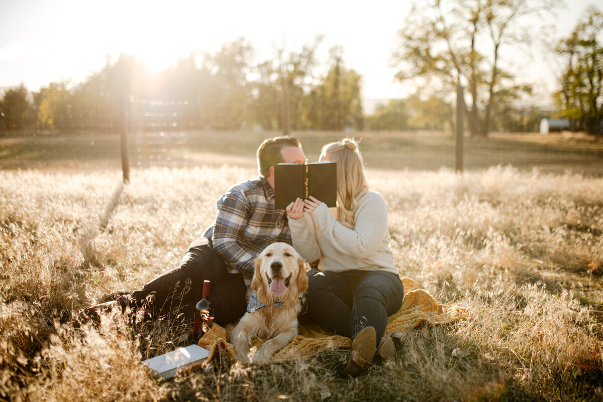 couple portrait of couple kissing behind book with dogs