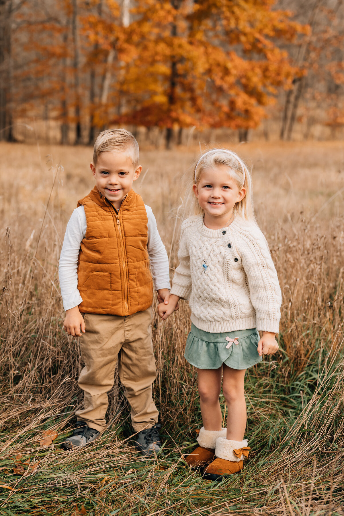 siblings-hold-hands-near-amber-trees