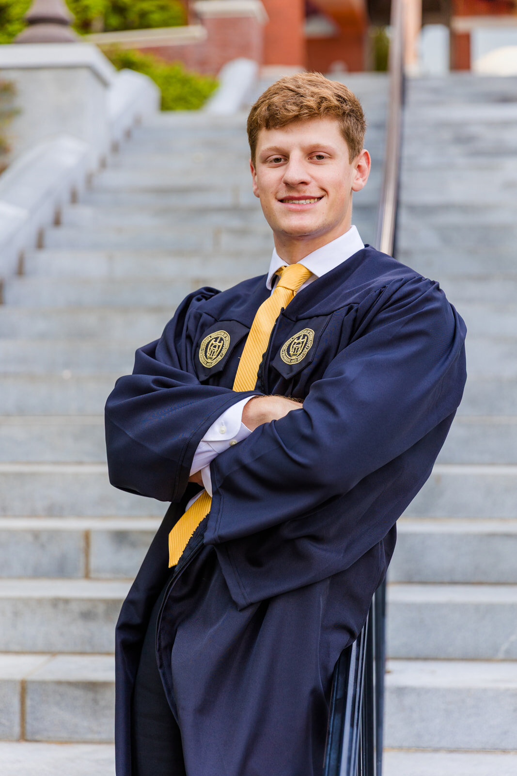 Senior boy standing arms crossed leaning against a stairs railway during graduation portrait on Georgia Tech campus during photoshoot with Atlanta photographer Laure Photography 