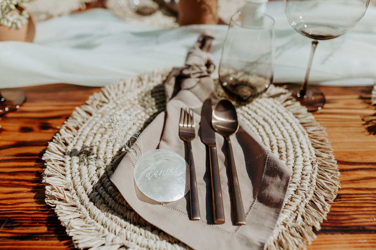 Boho place setting with a calligraphy capiz shell place card and flatware