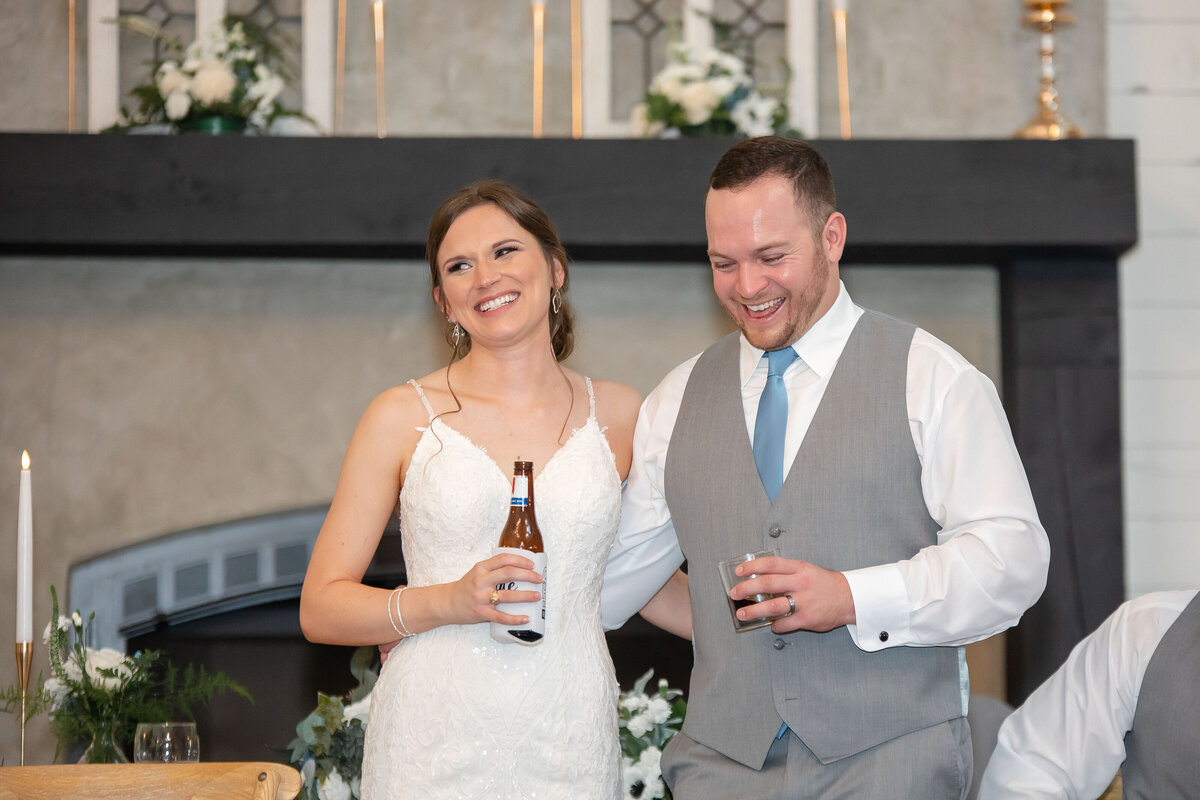 bride and groom laugh at speech while holding drinks at Texas wedding