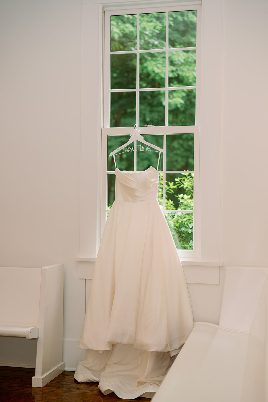 Simple classic wedding dress displayed by a large window at The Morris Estate bridal suite in Niles Michigan.
