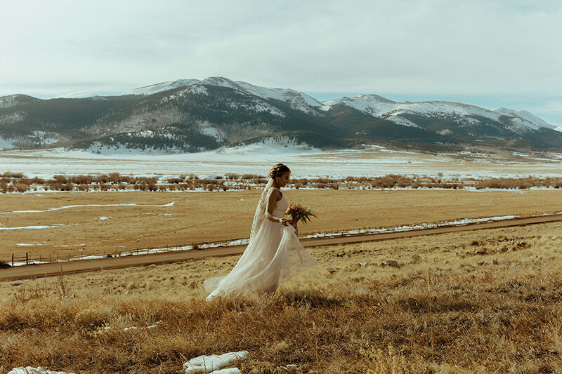 colorado bride walking  with  mountains in background for elopement