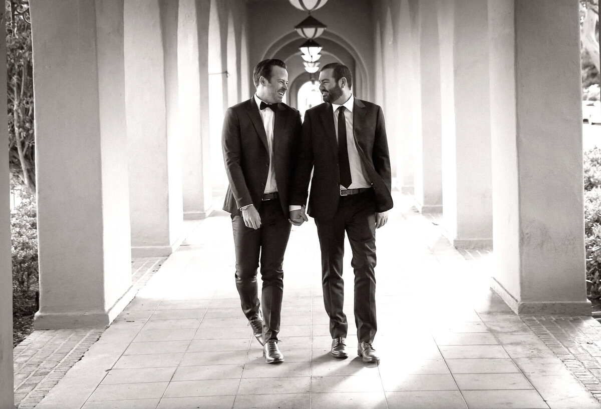 elegant-lgbtq-grooms-holding-hands-archway-walkway