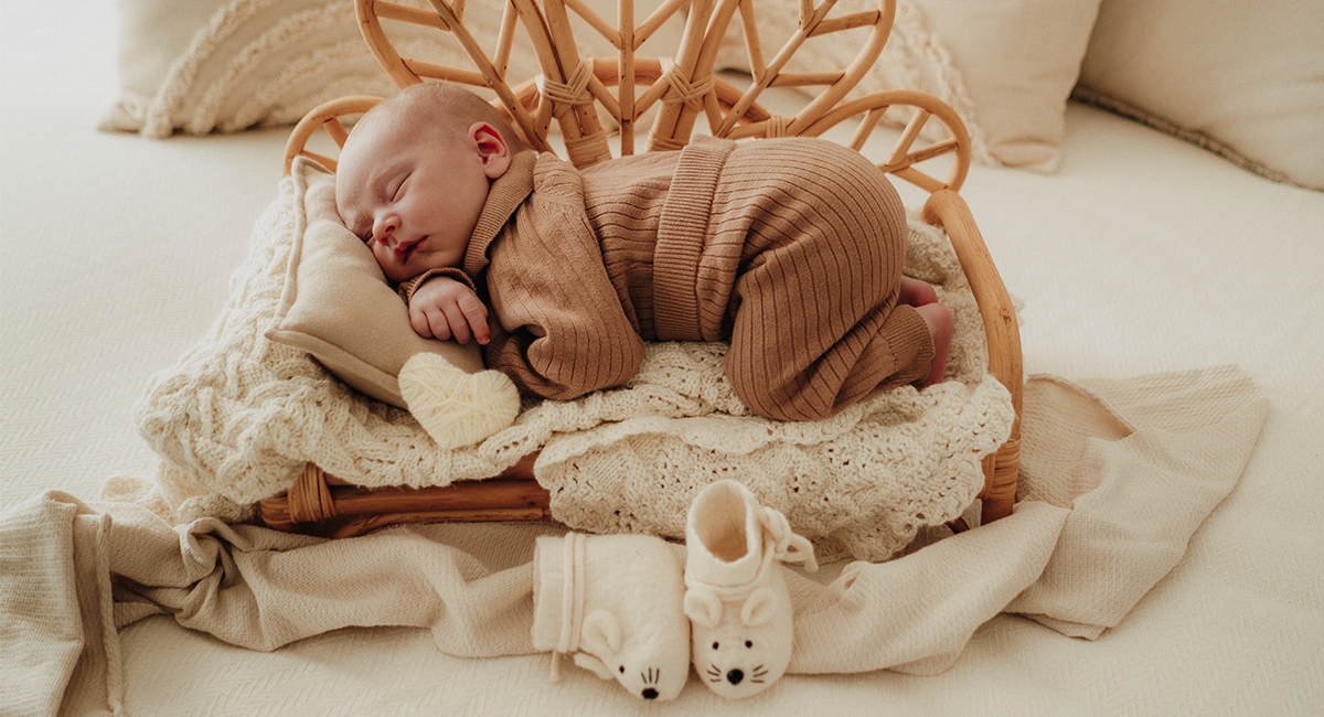 Kleines Baby liegt auf einem Rattan-Bettchen