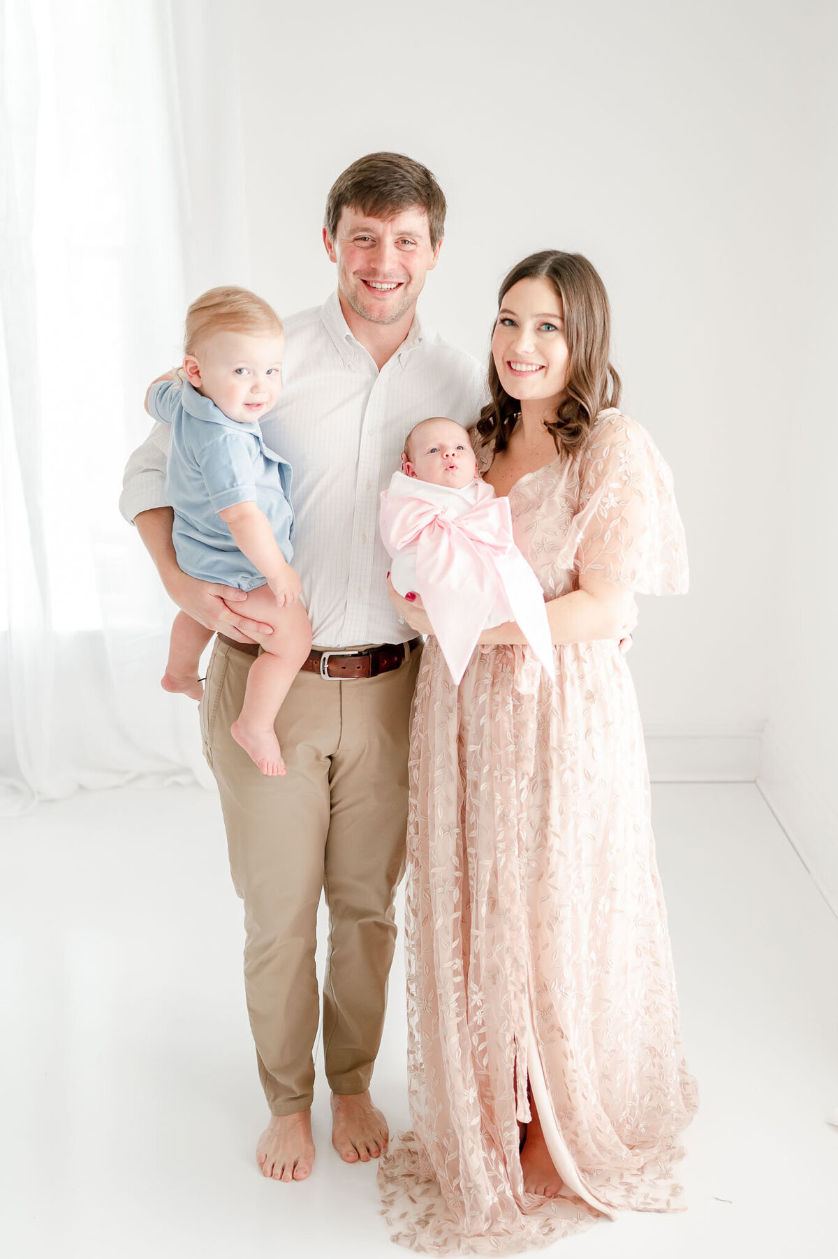Family of 4 with a newborn smiles in Nashville newborn photographer Kristie Lloyd's studio