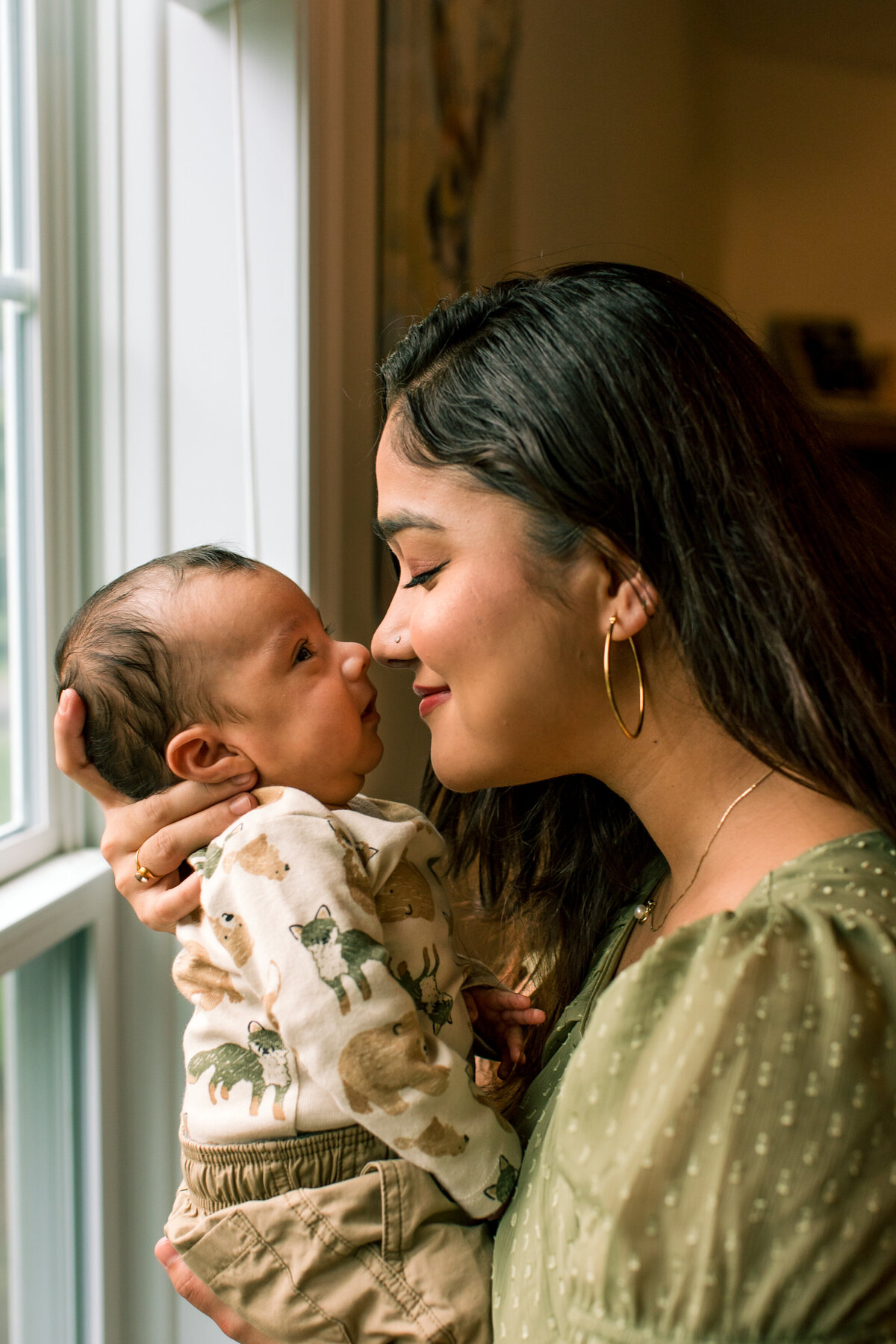 Family photo in Boone, NC of a mom touching noses with her infant son during a newborn photo session.