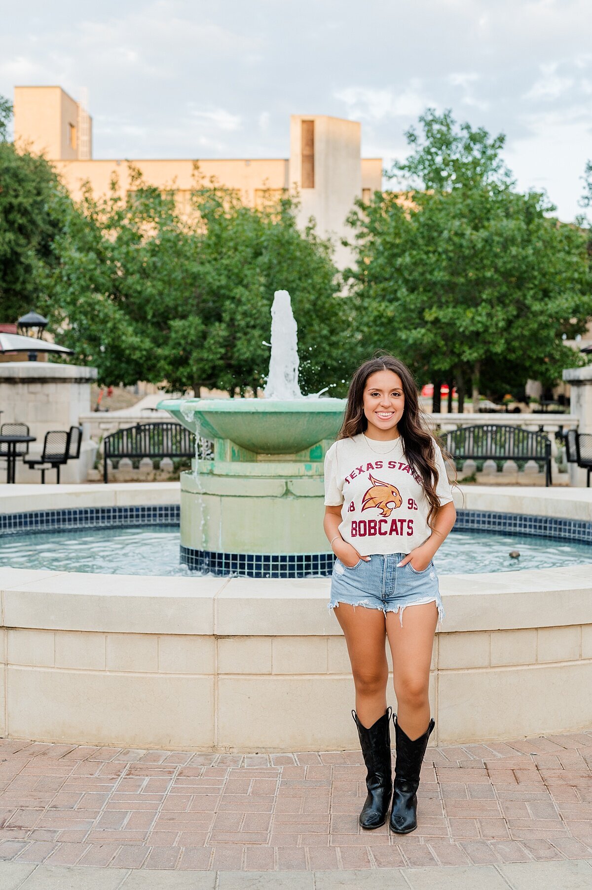 Texas State grad posing by the fountain 