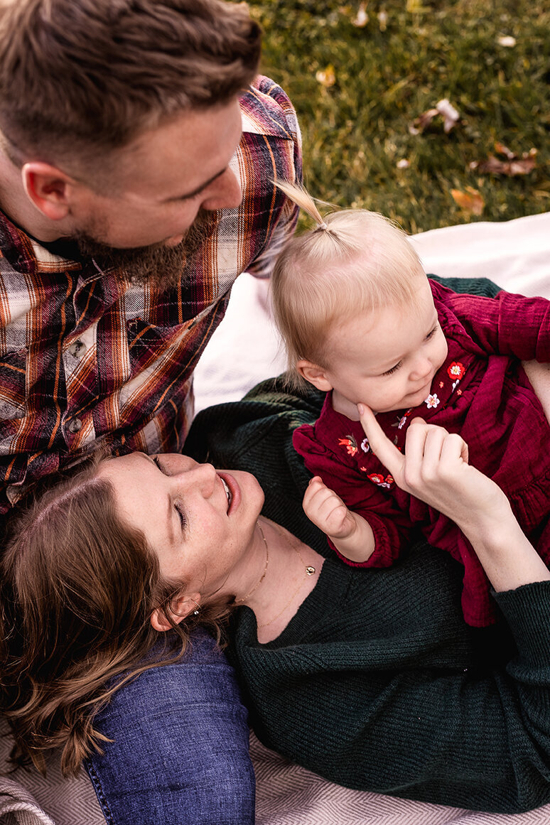 Mom laying on blanket and gently touching baby's cheek at family photo session in Bedford Commons in Bedford NH by Lisa Smith Photography