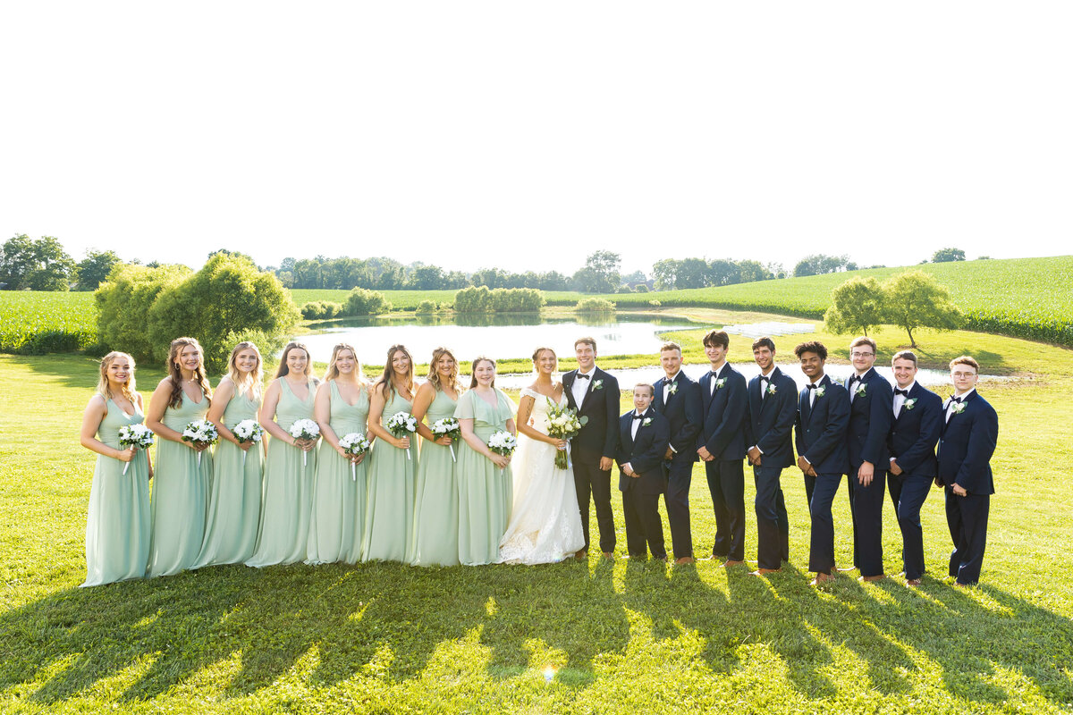 Wedding party portraits with bridesmaids in pale green dresses and groomsmen in black suits at The Ruby Cora wedding venue in Clarksville, TN