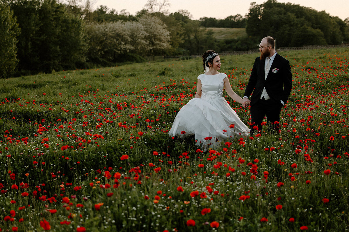 bride and groom walking together in a flower field