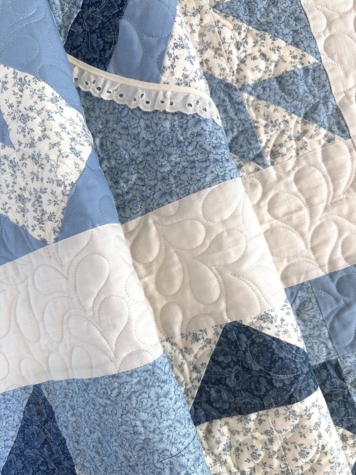 This blue and white quilt features the all-over feather quilting design