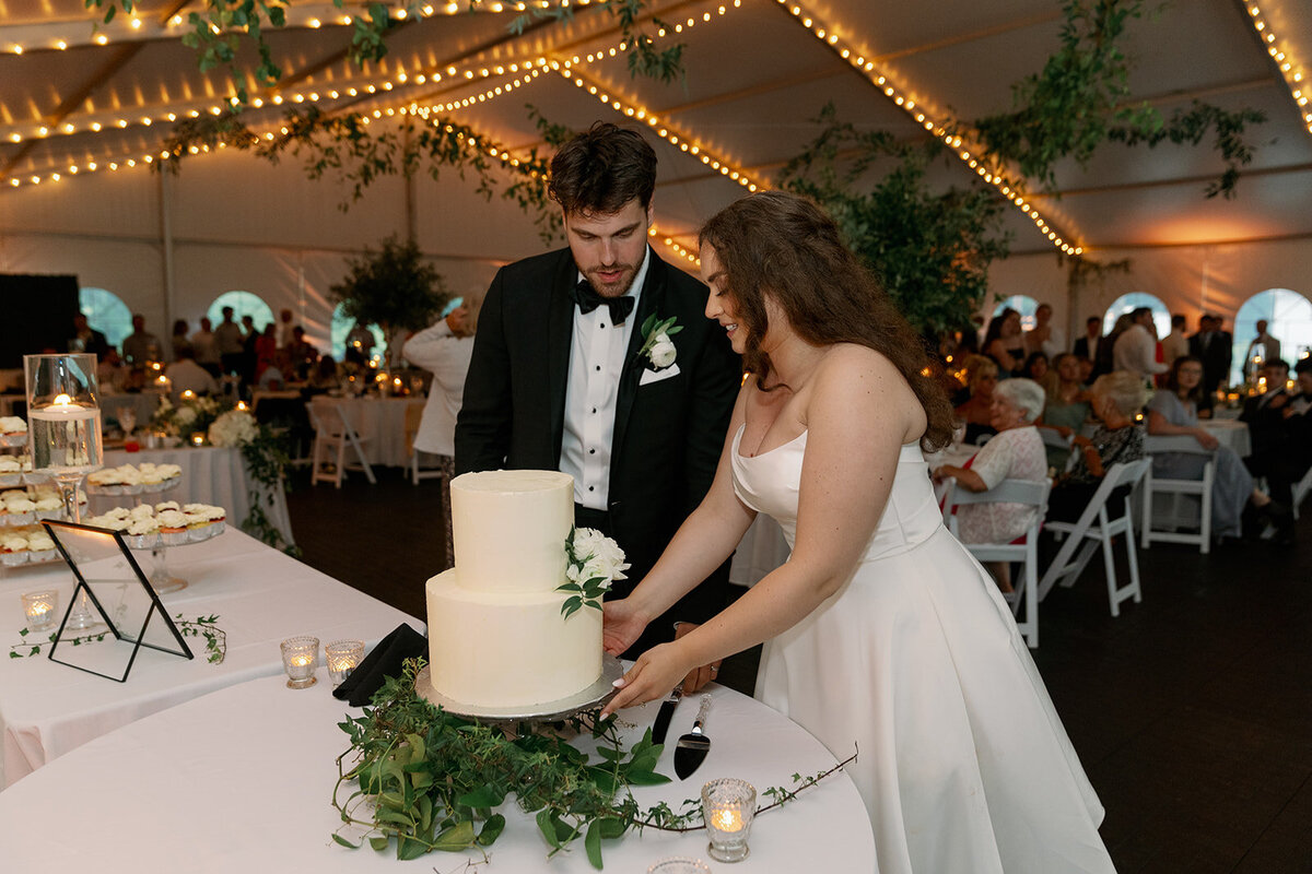 Couple cutting their wedding cake during their reception at The Morris Estate tented venue.