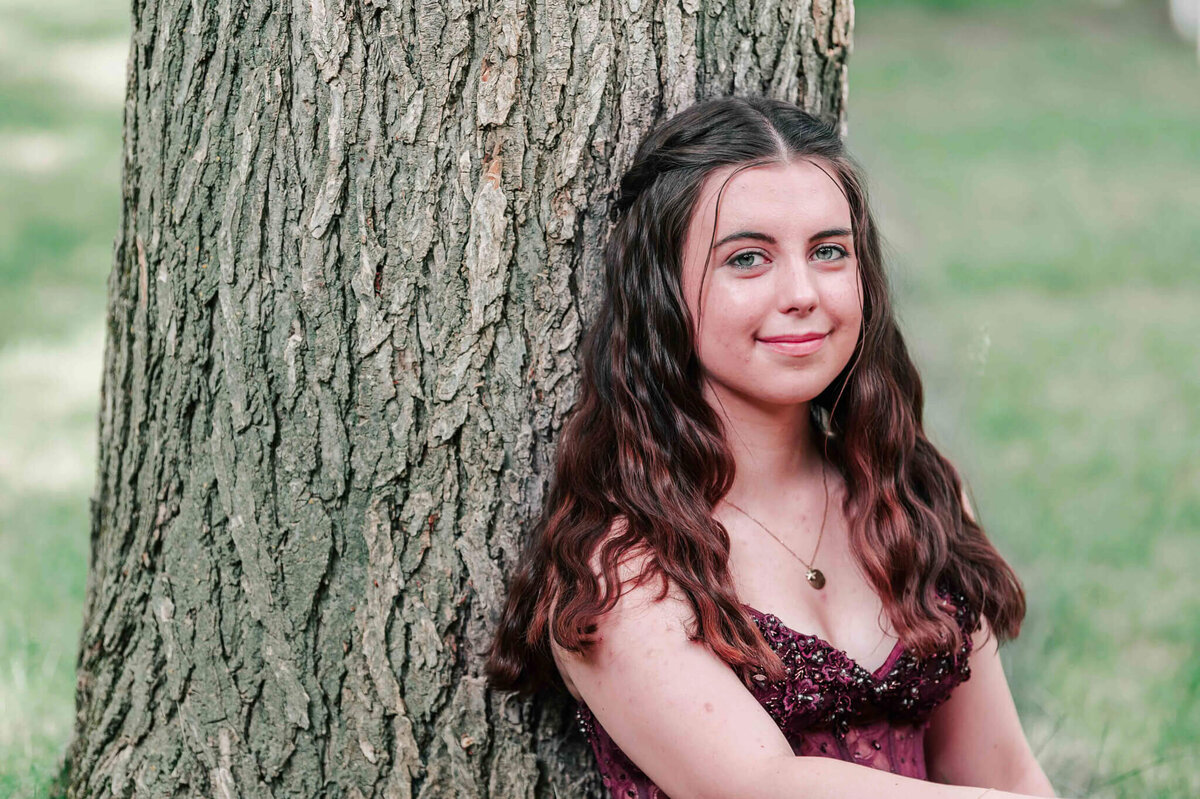 Leaning on a tree while sitting. Close up of her face. 