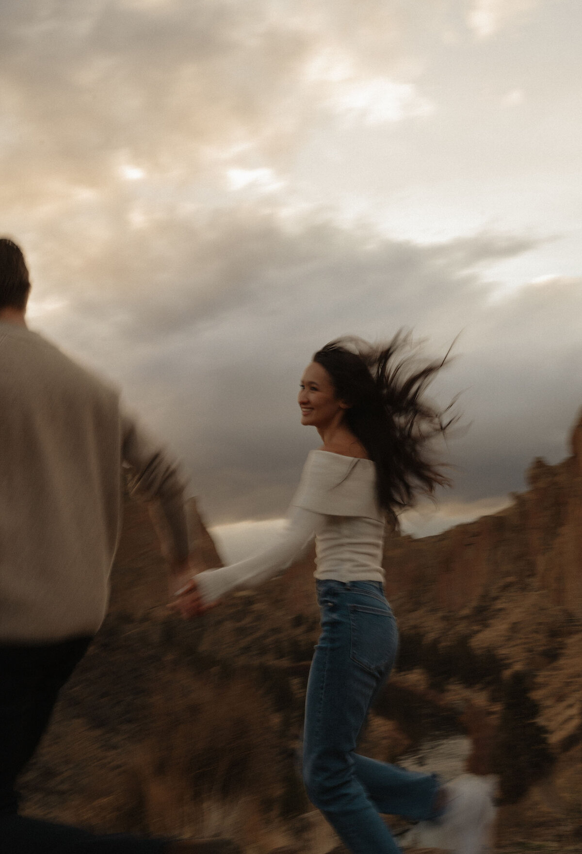 silly and fun moment of engaged couple running and smiling at Smith Rock in Bend Oregon