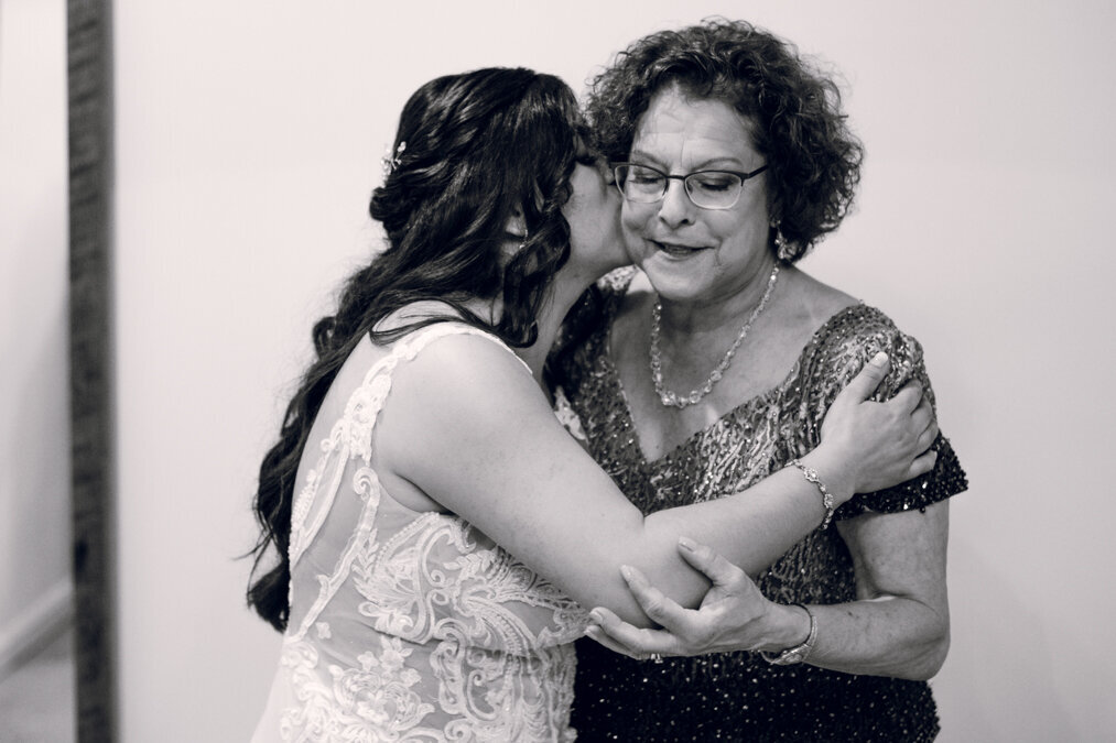 A black and white photo of a bride hugging her mother.