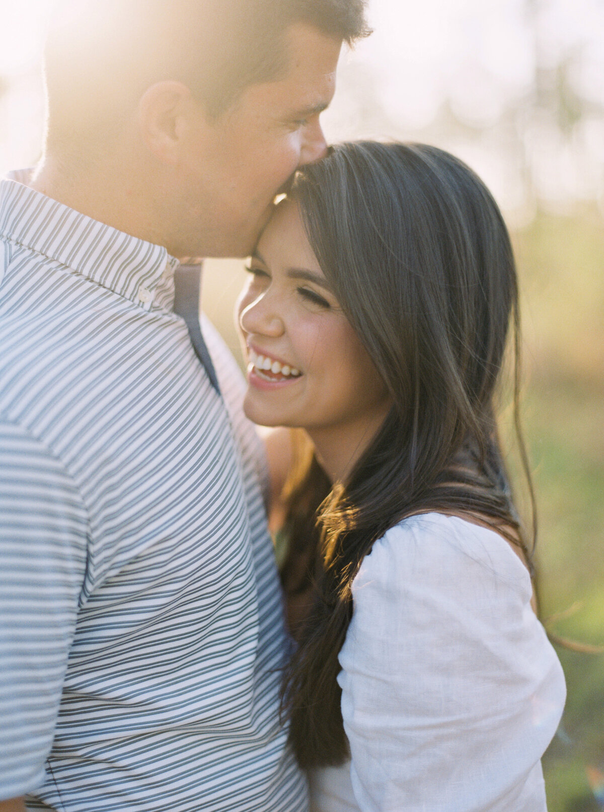 Man kisses his fiance's forehead as she smiles