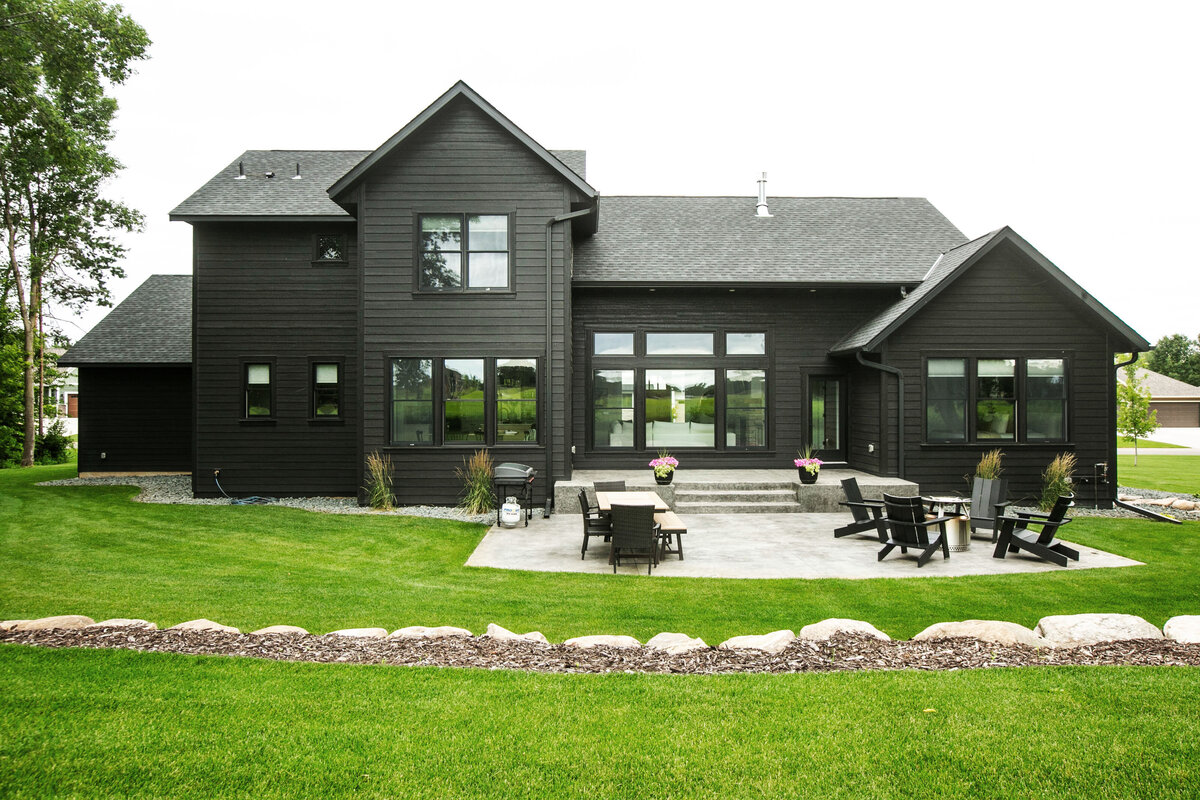 Exterior view of custom home in Otsego, Minnesota with black siding, large patio and windows built by Cornerstone Custom Builds
