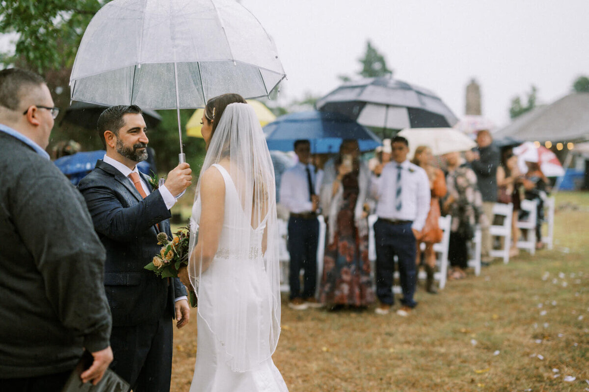 couple-stands-under-umbrella-during-raining-ceremony