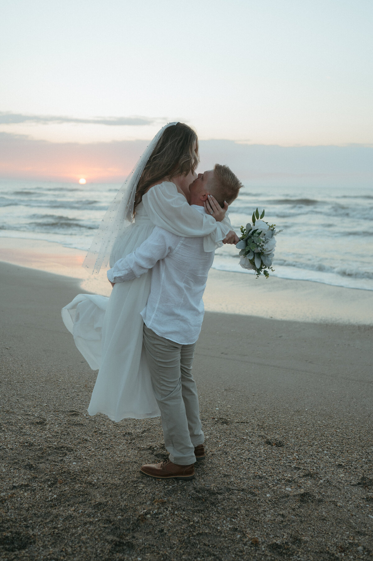 groom holding bride at florida beach