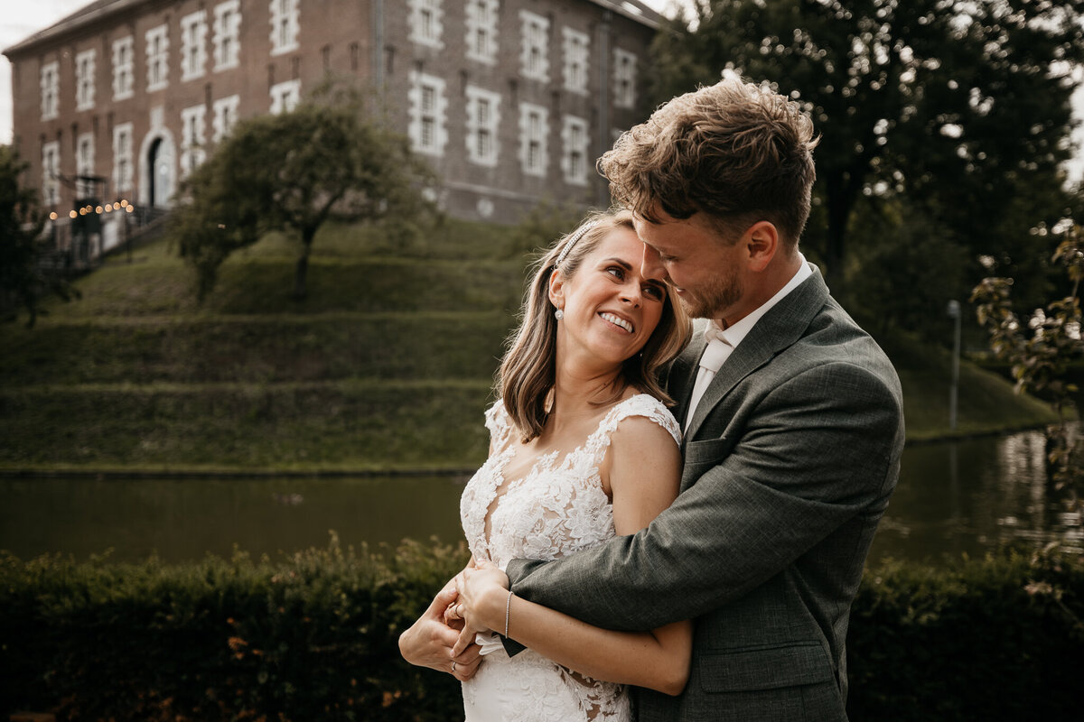 en bruid en bruidegom delen een intiem moment met een idyllisch kasteel als achtergrond, vastgelegd door IMAI Wedding.