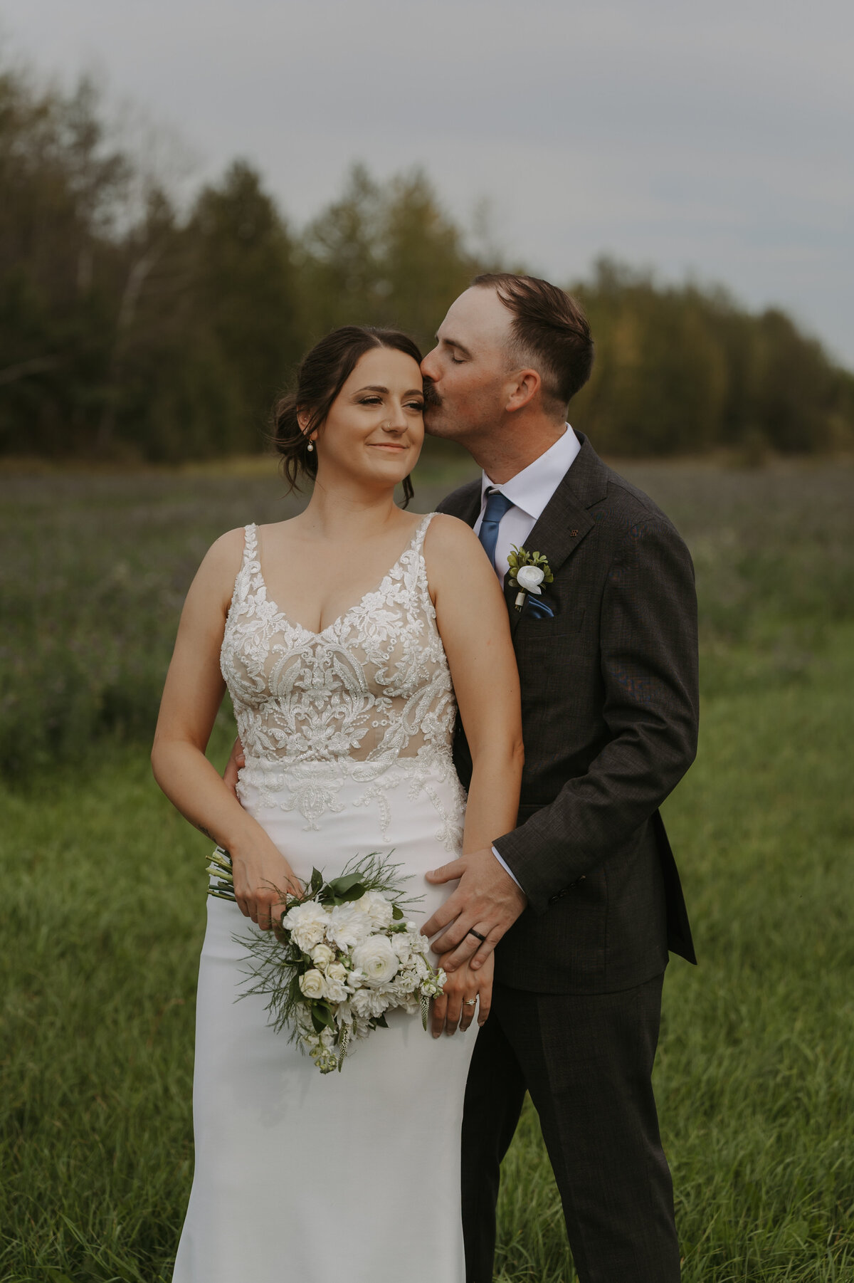 bride and groom standing in field on wedding day