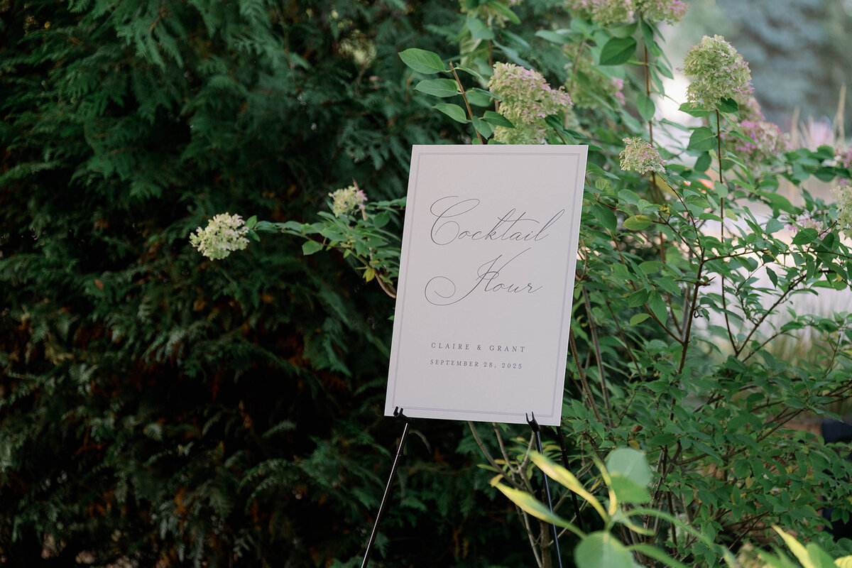 Wedding welcome sign surrounded by greenery at Café Cortina reception in Farmington Hills Michigan.