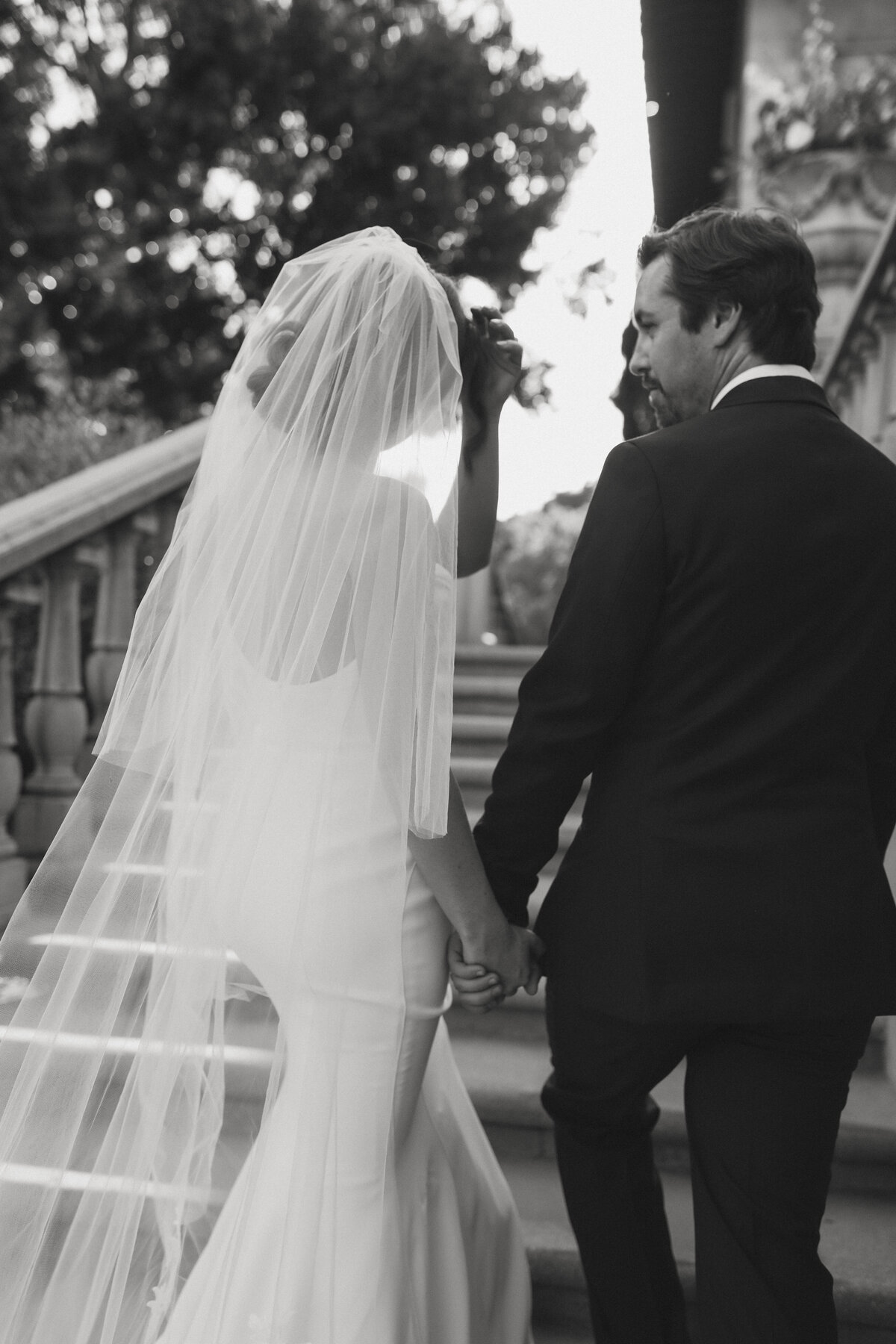 bride and groom holding hands on stairs looking at each other