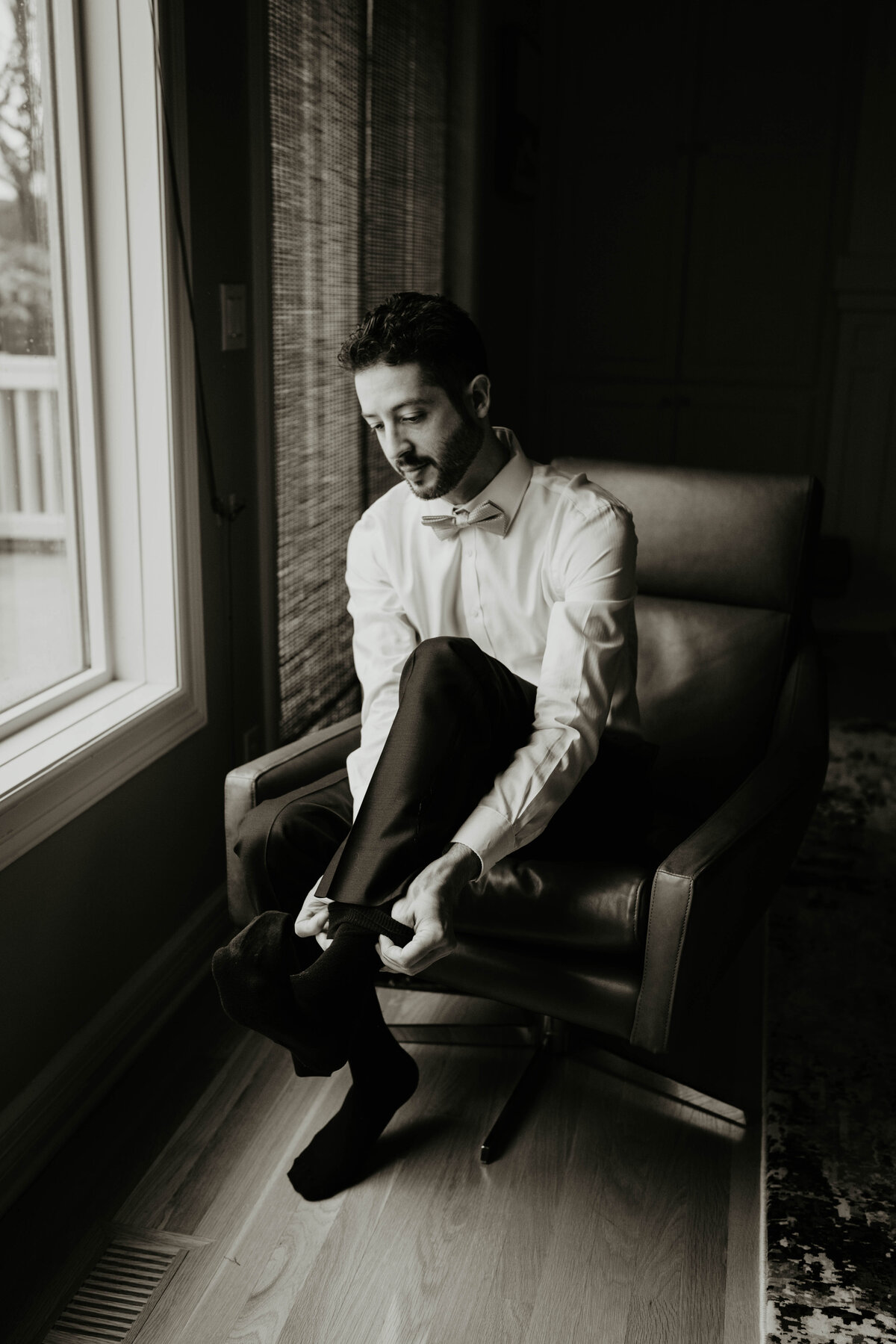 Groom putting on his socks while getting ready for his wedding