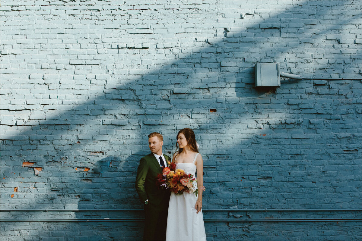 bride and groom standing in front of blue wall
