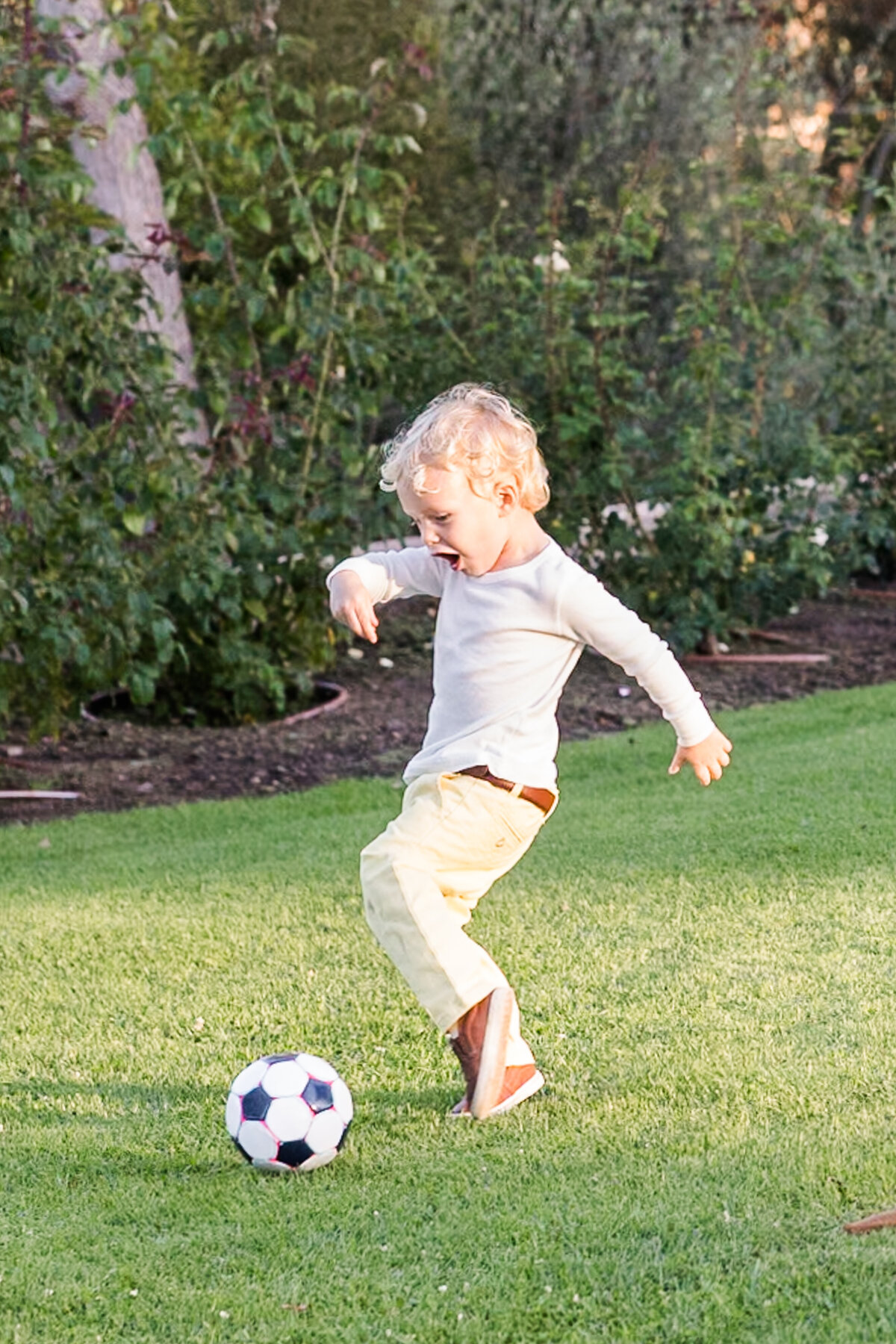 young boy kicking soccer  ball in san diego park