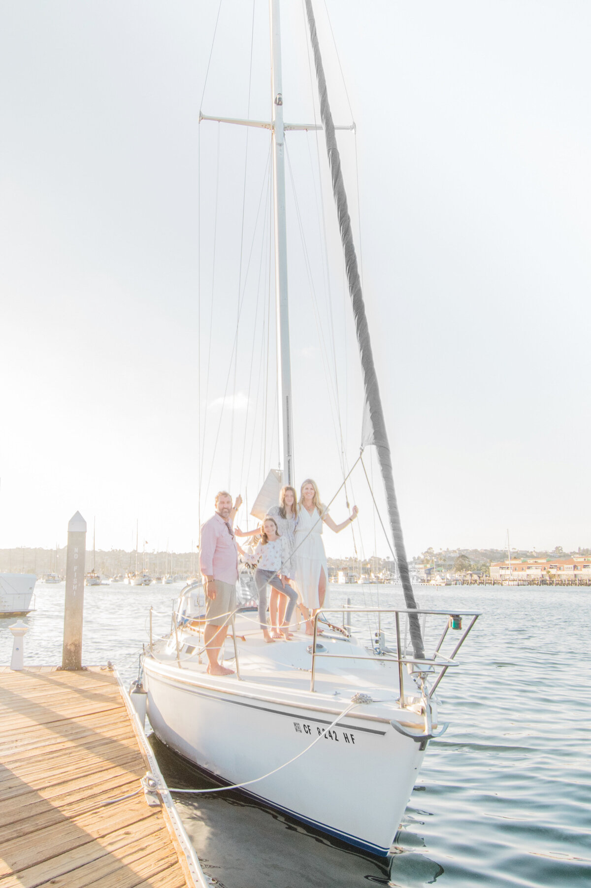 Family Photographer, a young family stands on sailboat docked at the pier