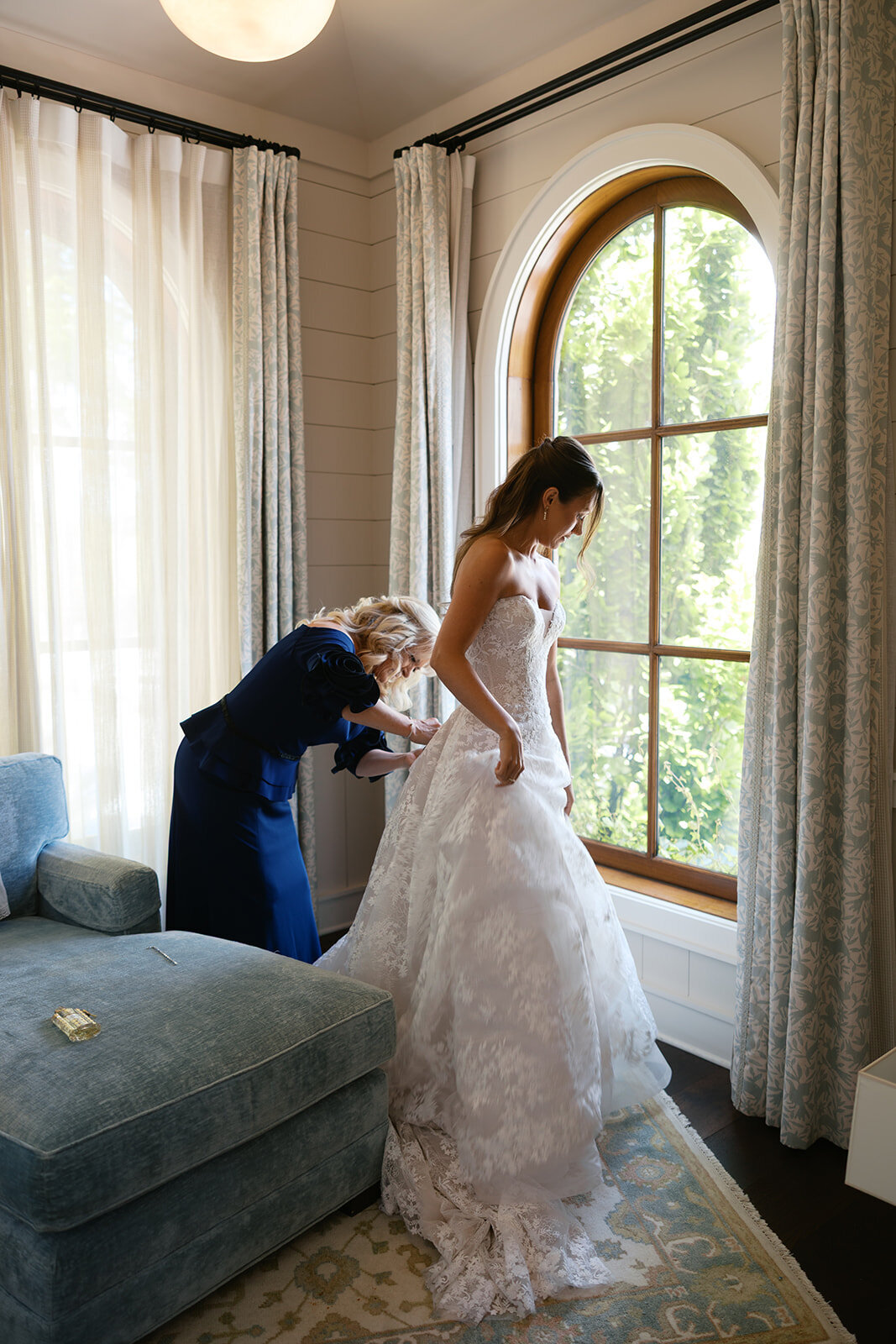 Mother helps bride into lace wedding gown in a serene suite at Old Edwards Inn.