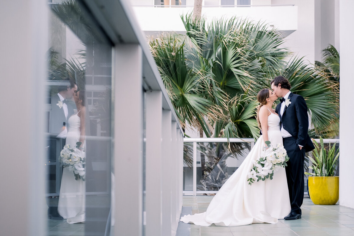 Bride and Groom kiss on the palm filled balcony of the Miami Wedding venue