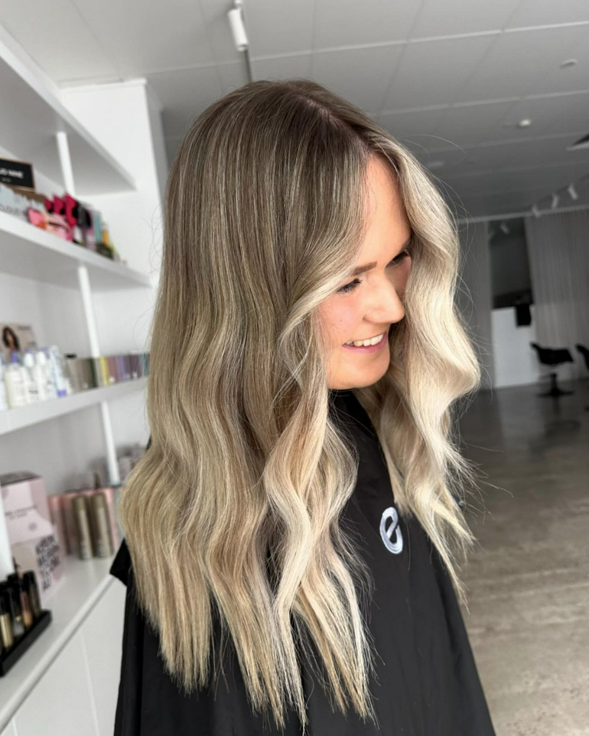 Woman I black hairdresser cape with freshly coloured hair - brunette with blonde pieces