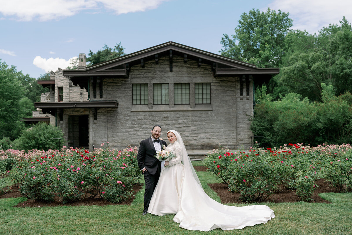 Bride and groom walking through the rose gardens at Henry Ford Estate, captured by a Michigan wedding photographer.