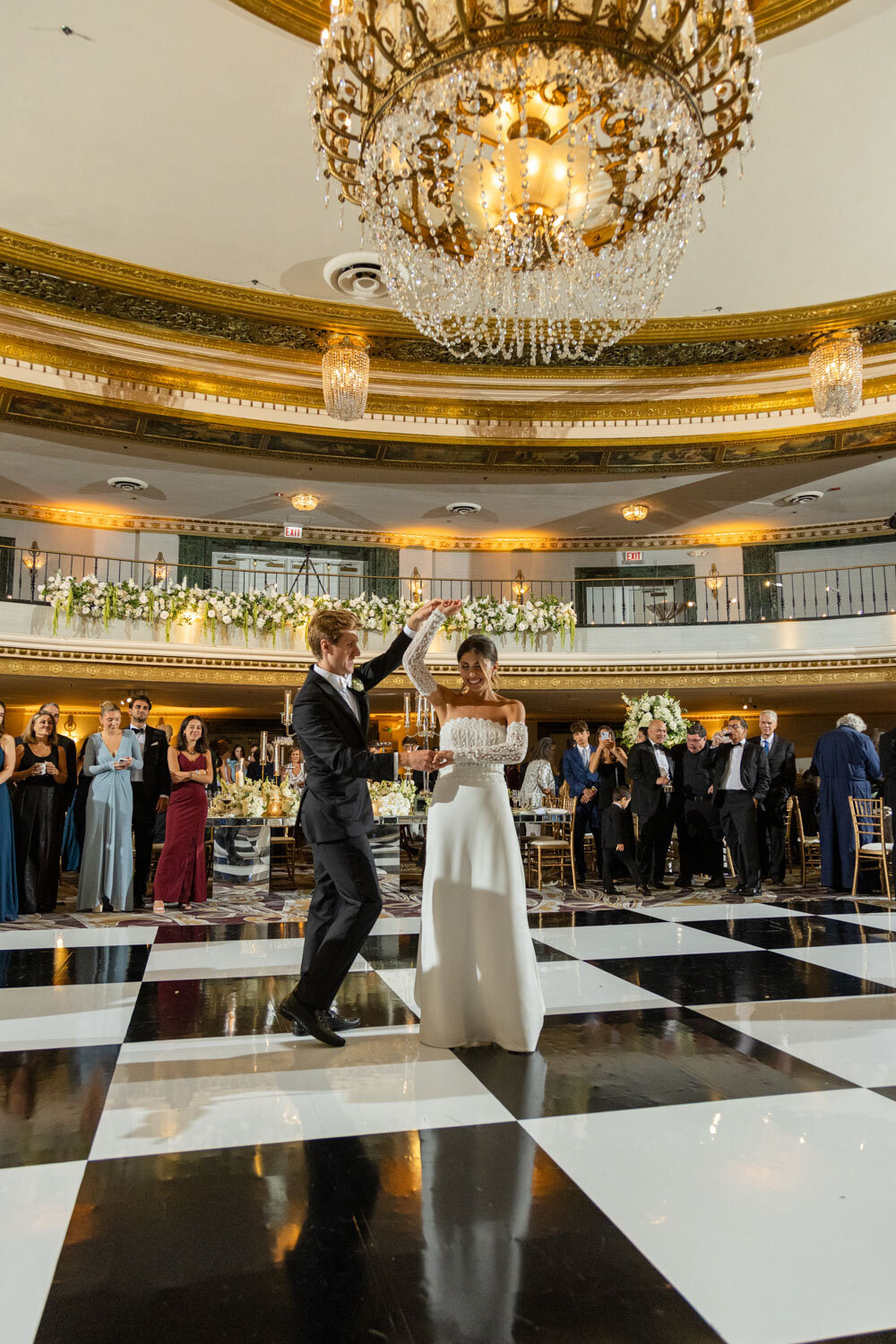 A bride and groom are dancing in a large room