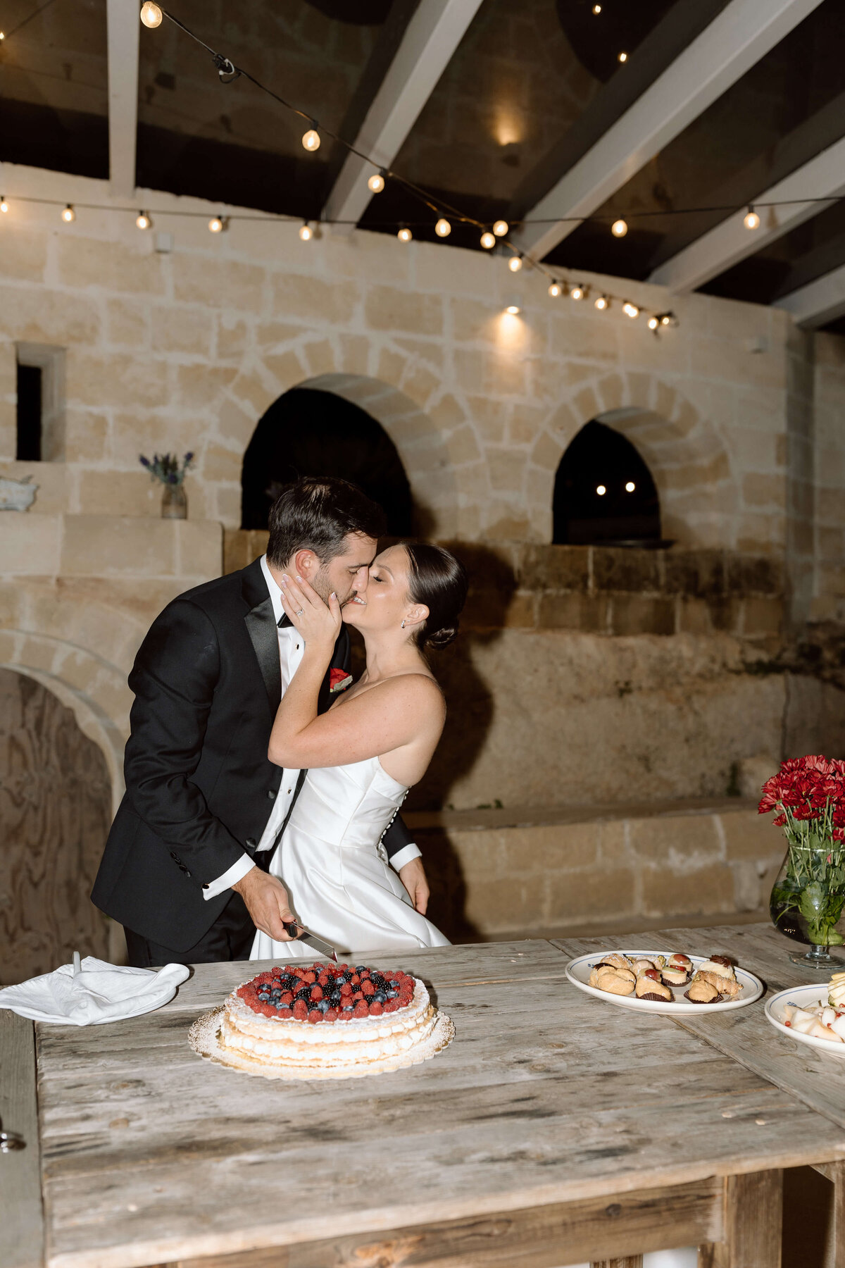 A couple cutting their fruit flan cake.
